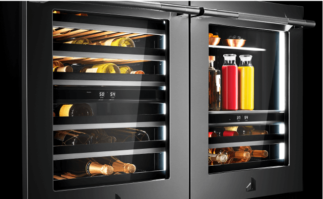 A JennAir undercounter refrigerator with wine bottles, champagne bottles, bowls of berries and pitchers of juice.